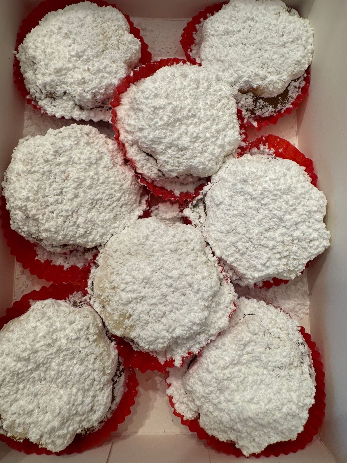 Eight large, flower-shaped Gluten-Free Alfajores in red paper cups.